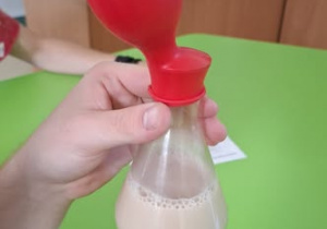 Uczeń potrząsa kolbą, balonik lekko nadmuchany.