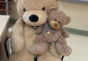 Duzy i mały miś siedzą na krześle obok ławki.