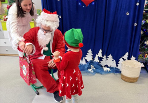 Mikołaj wręcza prezent dziecku.