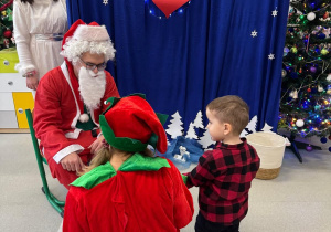 Mikołaj wręcza prezent dziecku.