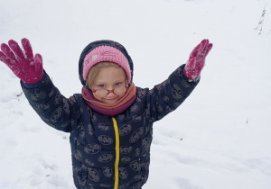 Uśmiechnięta dziewczynka z rękoma w górze.