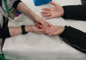 Uczennica masuje klientkę stoiska.