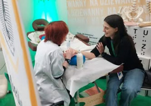 Uczennica masuje klientkę stoiska.