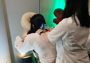 Uczennica masuje klientkę stoiska.