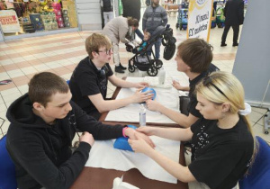 Uczniowie masują dłonie i nadgarstki.