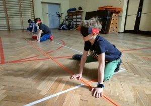 Dzieci w goglach kucają w oczekiwaniu na piłkę.