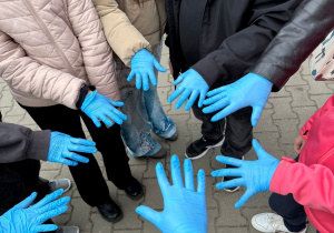Uczniowie w gumowych rękawiczkach gotowi do sprzątania.