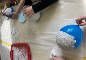 Uczniowie pokrywają paskami gipsowymi balony.