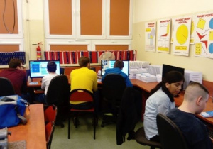 Uczniowie wspólnie z instruktorami siedzący przy komputerach
