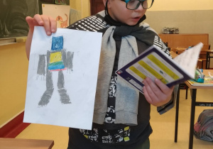 Uczeń czytający z zeszytu o swoim narysowanym robocie
