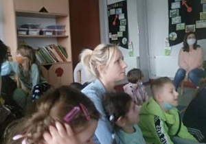 Dzieci siedzące na podłodze i słuchające dźwięków miasta.