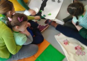 Dziewczynki ozdabiają namalowane farbami wiosenne drzewo