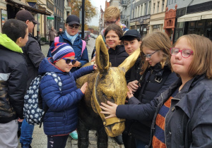Uczniowie wokół rzeźby osła na Starym Mieście w Toruniu.